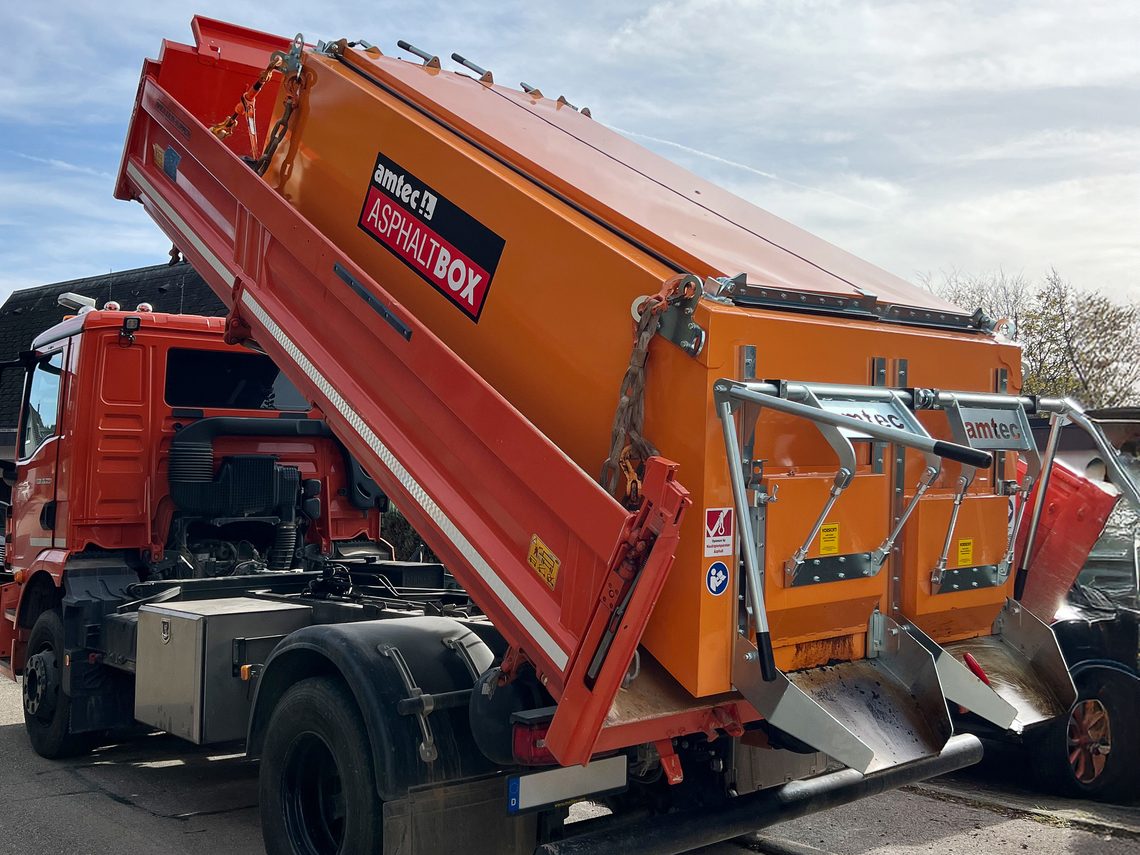 amtec Asphaltbox mit ThermoTOP-Heizsystem auf einem Lkw-Abrollkipper beim Abkippen